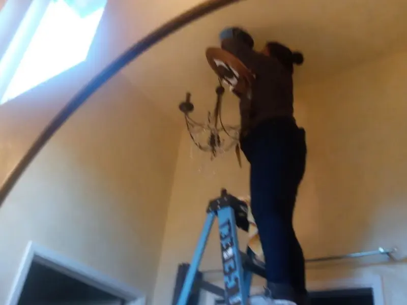 Electrician installing a chandelier in a Vicksburg residence